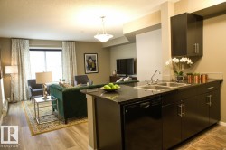 Kitchen featuring open floor plan, dishwasher, a peninsula, pendant lighting, and a textured ceiling - 