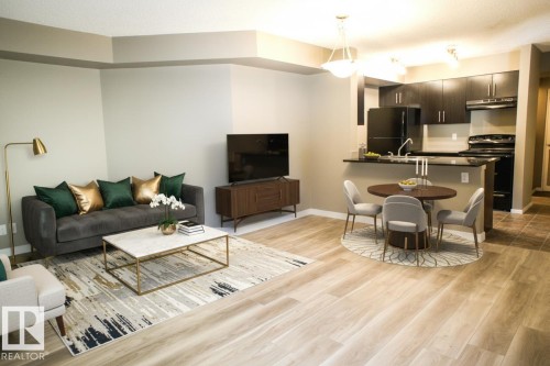Living room featuring light wood-style floors and baseboards - 104 5804 Place Nw, Edmonton, AB - Indoor Photo Showing Living Room