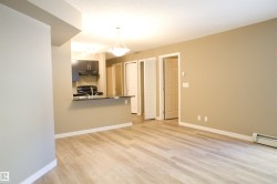 Kitchen with a peninsula, light wood finished floors, pendant lighting, dark countertops, and electric range - 