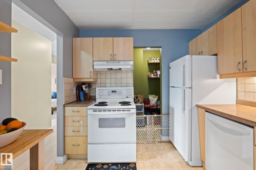 Kitchen featuring white appliances, light wood finish cabinetry, tasteful backsplash, a textured ceiling, and light countertops - 1925 Saddleback Road, Edmonton, AB - Indoor Photo Showing Kitchen
