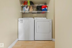 Laundry area with light wood-style flooring and washing machine and clothes dryer - 