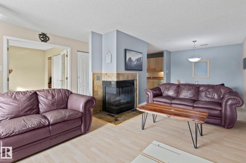 Living area featuring light wood-style floors, a tile fireplace, and a textured ceiling - 1925 Saddleback Road, Edmonton, AB - Indoor Photo Showing Living Room With Fireplace