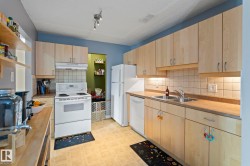 Kitchen featuring light wood finish cabinets, white appliances, light floors, open shelves, and light countertops - 
