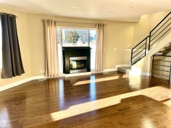 Unfurnished living room featuring dark wood-style floors, a glass covered fireplace, stairs, and recessed lighting - 