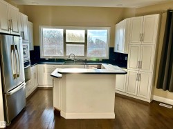 Kitchen featuring appliances with stainless steel finishes, healthy amount of natural light, white cabinetry, and a kitchen island - 