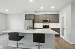 Kitchen featuring decorative backsplash, a kitchen island with sink, stainless steel appliances, a kitchen breakfast bar, and light wood-style flooring - 