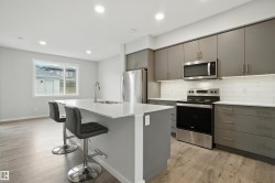 Kitchen with gray cabinets, tasteful backsplash, appliances with stainless steel finishes, light wood-style flooring, and recessed lighting - 