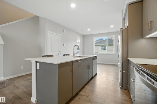 Kitchen with light wood-type flooring, recessed lighting, stainless steel appliances, gray cabinetry, and an island with sink - 20727 25 Ave, Edmonton, AB - Indoor Photo Showing Kitchen