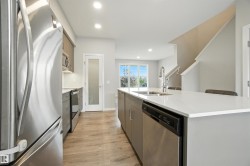 Kitchen with stainless steel appliances, recessed lighting, light wood-type flooring, a kitchen island with sink, and light stone countertops - 