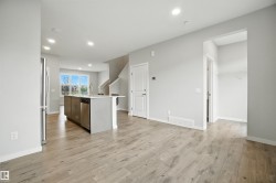 Kitchen with a center island with sink, recessed lighting, light wood-style floors, stainless steel appliances, and light stone counters - 