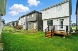 Back of property featuring a yard, a wooden deck, and a residential view - 
