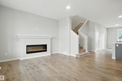 Unfurnished living room with stairway, light wood-style floors, a glass covered fireplace, and recessed lighting - 