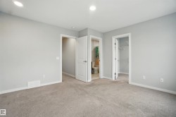 Unfurnished bedroom with a spacious closet, light colored carpet, recessed lighting, and ensuite bath - 