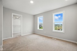Unfurnished bedroom with a walk in closet, light colored carpet, and recessed lighting - 
