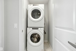 Washroom featuring stacked washer / drying machine and baseboards - 
