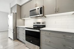 Kitchen featuring gray cabinets, stainless steel appliances, decorative backsplash, and light wood finished floors - 