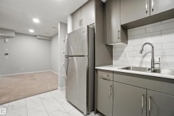 Kitchen with freestanding refrigerator, gray cabinetry, light countertops, decorative backsplash, and recessed lighting - 