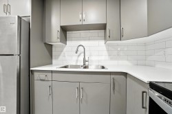 Kitchen featuring gray cabinetry, freestanding refrigerator, and backsplash - 