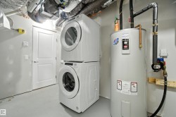 Laundry room with water heater and stacked washer and clothes dryer - 