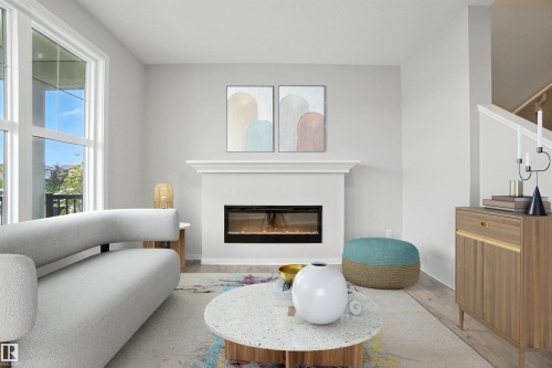 Living room featuring a glass covered fireplace and wood finished floors - 20727 25 Ave, Edmonton, AB - Indoor Photo Showing Living Room With Fireplace