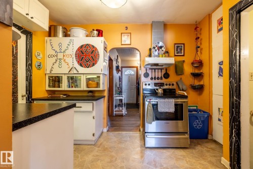 Kitchen featuring stainless steel range with electric cooktop, white cabinets, arched walkways, and dark countertops - 11240 84 Street, Edmonton, AB - Indoor Photo Showing Kitchen