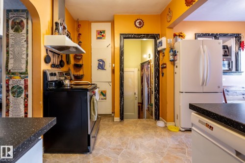Kitchen with dark countertops, white appliances, washer / dryer, and arched walkways - 11240 84 Street, Edmonton, AB - Indoor Photo Showing Kitchen