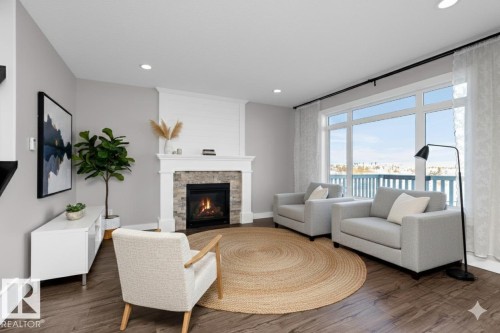 Living area featuring wood finished floors, a stone fireplace, and recessed lighting - 62 Ellice Bend, Fort Saskatchewan, AB - Indoor Photo Showing Living Room With Fireplace