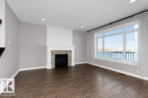 Unfurnished living room featuring dark wood-style flooring, a large fireplace, and recessed lighting - 62 Ellice Bend, Fort Saskatchewan, AB - Indoor Photo Showing Living Room With Fireplace