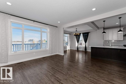 Unfurnished living room featuring dark wood finished floors, a textured ceiling, and a chandelier - 62 Ellice Bend, Fort Saskatchewan, AB - Indoor Photo Showing Other Room