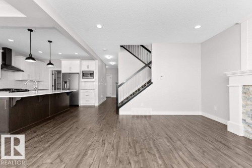 Unfurnished living room featuring dark wood-style flooring, a textured ceiling, and recessed lighting - 62 Ellice Bend, Fort Saskatchewan, AB - Indoor Photo Showing Kitchen With Upgraded Kitchen