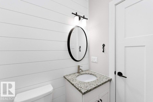 Half bath featuring vanity and wooden walls - 62 Ellice Bend, Fort Saskatchewan, AB - Indoor Photo Showing Bathroom