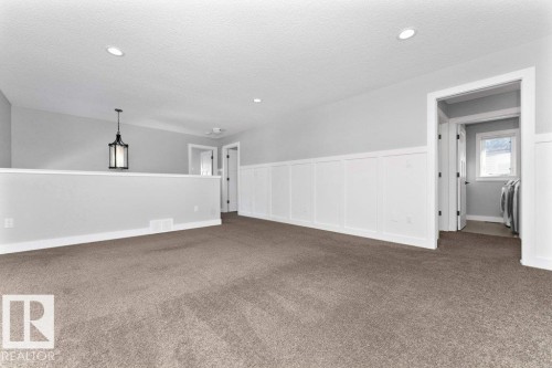 Carpeted empty room featuring a decorative wall and a wainscoted wall - 62 Ellice Bend, Fort Saskatchewan, AB - Indoor Photo Showing Other Room