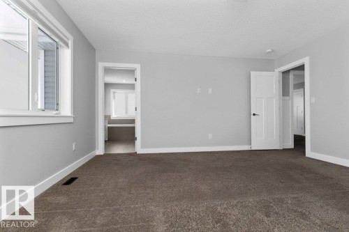 Unfurnished bedroom featuring dark colored carpet, connected bathroom, and a textured ceiling - 62 Ellice Bend, Fort Saskatchewan, AB - Indoor Photo Showing Other Room