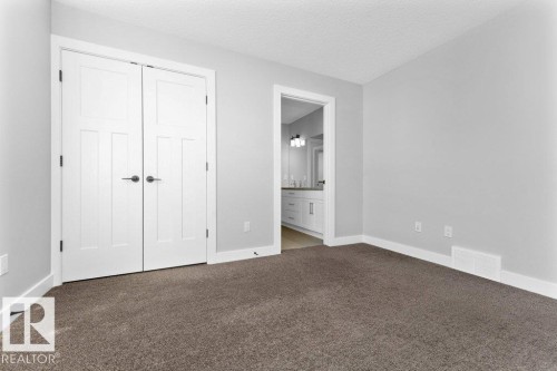 Unfurnished bedroom featuring carpet, a textured ceiling, ensuite bathroom, and a closet - 62 Ellice Bend, Fort Saskatchewan, AB - Indoor Photo Showing Other Room