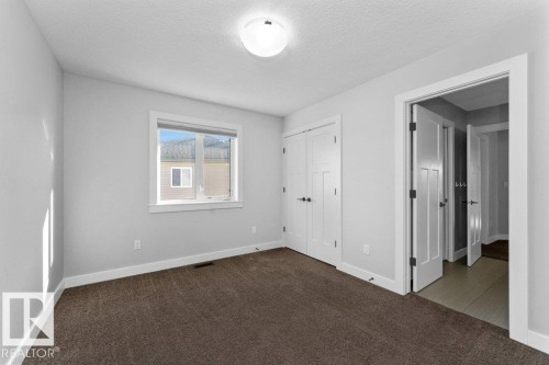 Unfurnished bedroom with dark colored carpet, a textured ceiling, and a closet - 62 Ellice Bend, Fort Saskatchewan, AB - Indoor Photo Showing Other Room