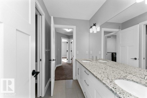 Bathroom with double vanity, a textured ceiling, and light tile patterned floors - 62 Ellice Bend, Fort Saskatchewan, AB - Indoor Photo Showing Bathroom