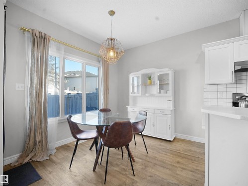 Dining room featuring a chandelier, light wood-type flooring, and a textured ceiling - 218 Hawks Ridge Boulevard, Edmonton, AB - Indoor Photo Showing Dining Room