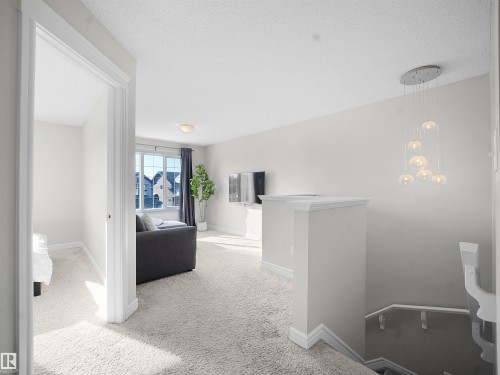 Hall with an upstairs landing, light colored carpet, and a textured ceiling - 218 Hawks Ridge Boulevard, Edmonton, AB - Indoor