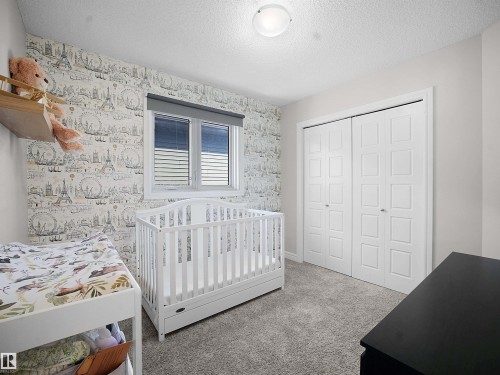 Bedroom with carpet flooring, a textured ceiling, a closet, and wallpapered walls - 218 Hawks Ridge Boulevard, Edmonton, AB - Indoor Photo Showing Bedroom