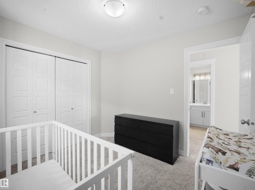 Bedroom featuring a closet, a crib, carpet, and a textured ceiling - 218 Hawks Ridge Boulevard, Edmonton, AB - Indoor Photo Showing Bedroom