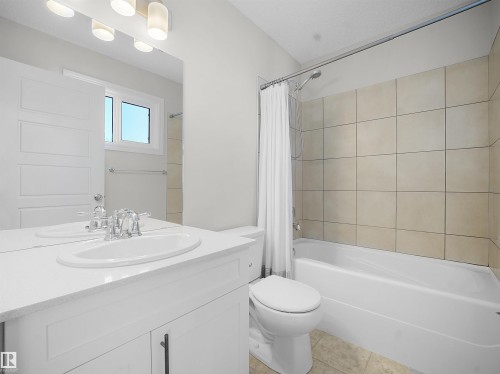 Full bath with vanity, shower / bath combination with curtain, and light tile patterned floors - 218 Hawks Ridge Boulevard, Edmonton, AB - Indoor Photo Showing Bathroom