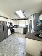Kitchen featuring a textured ceiling, appliances with stainless steel finishes, a skylight, dark countertops, and lofted ceiling - 