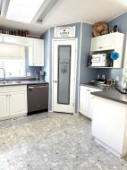Kitchen with white cabinetry, stainless steel appliances, dark countertops, a textured ceiling, and crown molding with a walk in pantry. - 