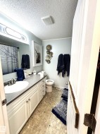 Full bathroom with vanity, a shower with shower curtain, light tile patterned flooring, and a textured ceiling - 
