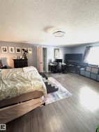 Primary Bedroom featuring wood finished floors, a desk, and a textured ceiling - 