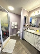 Full bath with a shower stall, a textured ceiling, vanity, and dark wood-style flooring - 