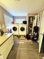Laundry area with a textured ceiling, dark wood-style floors, and washing machine and dryer - 