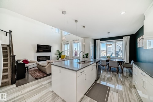Kitchen with white cabinets, pendant lighting, open floor plan, a glass covered fireplace, and healthy amount of natural light - 3716 46 Avenue, Beaumont, AB - Indoor Photo Showing Kitchen With Fireplace With Double Sink