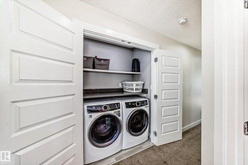 Laundry area featuring washer and clothes dryer, carpet flooring, and a textured ceiling - 3716 46 Avenue, Beaumont, AB - Indoor Photo Showing Laundry Room