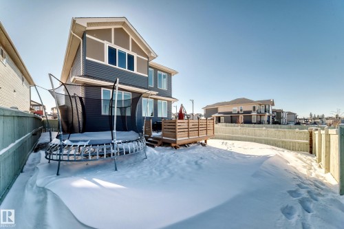 Rear view of property featuring a trampoline, a deck, and a fenced backyard - 3716 46 Avenue, Beaumont, AB - Outdoor